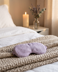 Lavendel-Augenmaske auf gemachtem Bett bei Kerzenlicht
